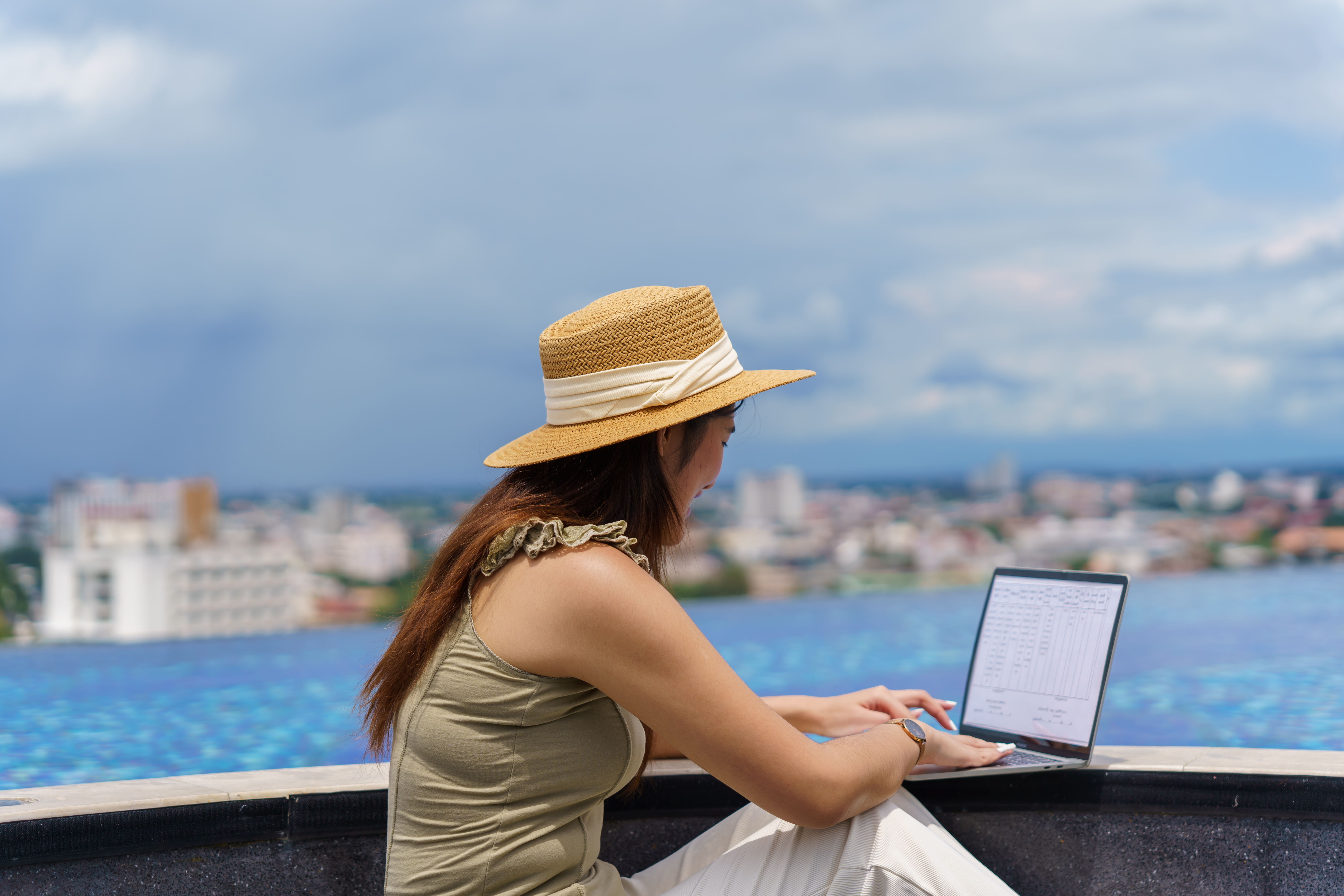 Asian woman digital nomad freelancer work typing laptopÂ on online meeting Remote workÂ happy working digital nomadÂ in sunny blue water pool