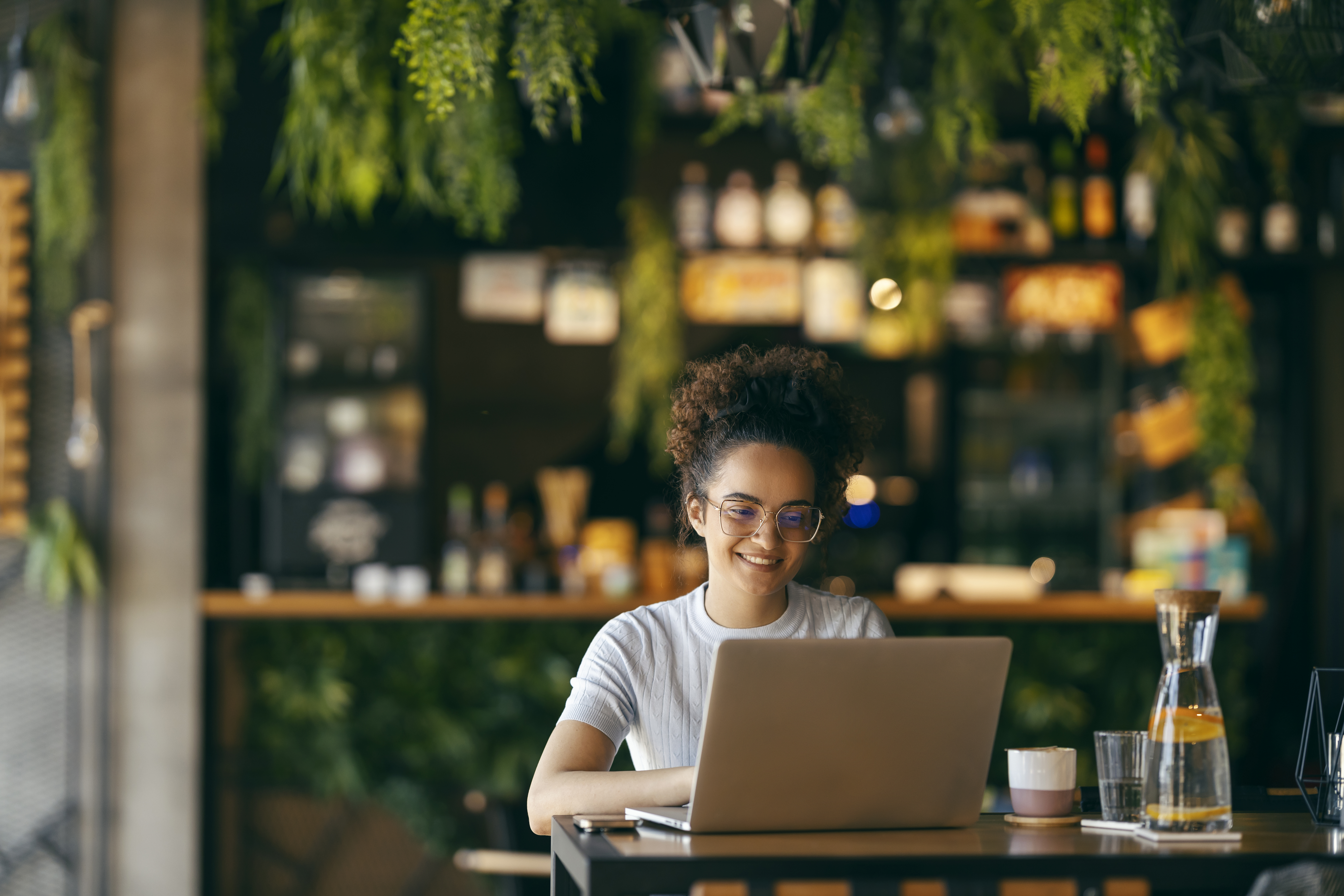 Portrait of happy freelancer sitting in cafe and typing on laptop. A girl is finishing her freelance project.