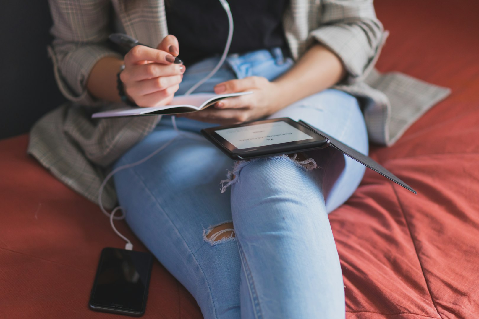 A woman reads an e-reader near a bookcase. an e-book against the background of paper books. ease of use of an e-book. a modern way to read books.